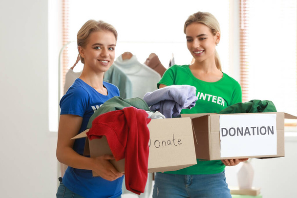 Ehrenamtliche Helferinnen halten Kartons mit Kleidungsstücken für die Spende im Raum - Foto, Bild
