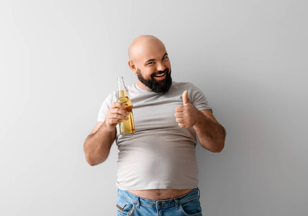 łysy mężczyzna z piwem pokazuje kciuk w górę na jasnym tle - Zdjęcie, obraz