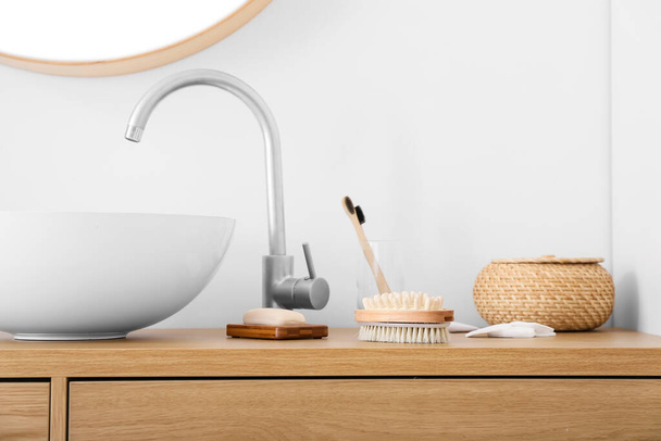 Különböző kefék és fürdőkellékek az asztalon a mosogató közelében - Fotó, kép