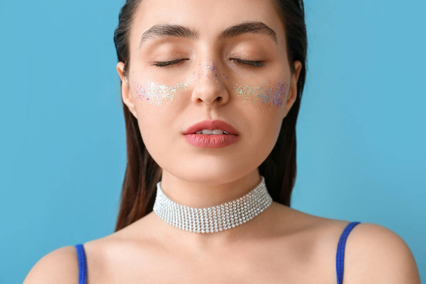 Жінка з креативним макіяжем і закритими очима на синьому фоні
 - Фото, зображення