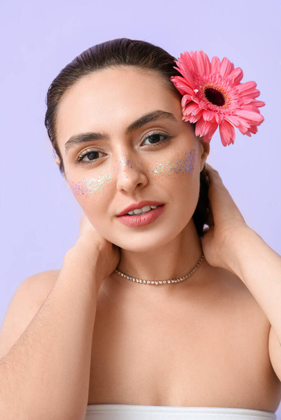 Portret van een mooie vrouw met creatieve make-up en gerbera bloem op kleur achtergrond - Foto, afbeelding