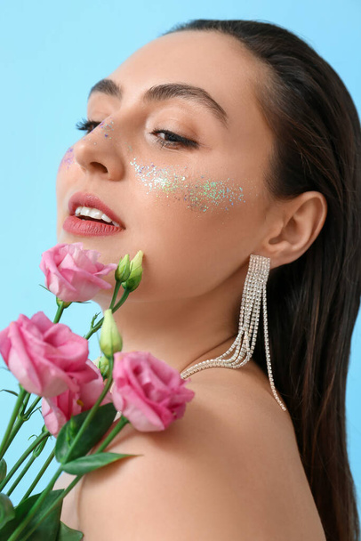 Femme avec maquillage créatif et roses sur fond bleu - Photo, image
