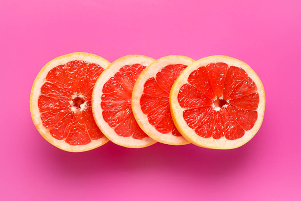 Slices of tasty ripe grapefruit on pink background - Photo, Image