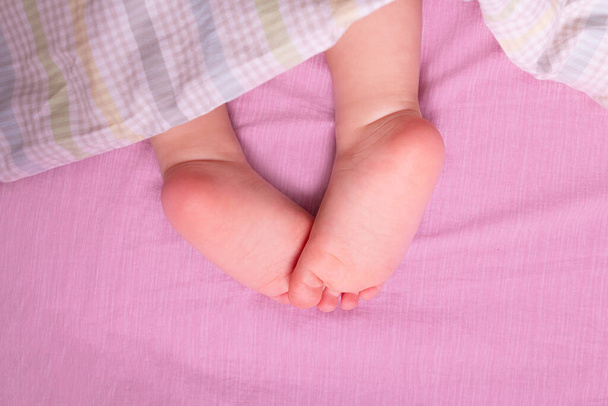 Caucasian baby bare legs in parents bed.  - Photo, Image