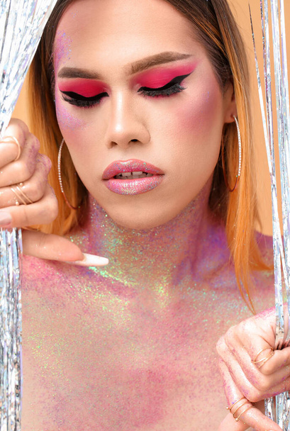 Fashionable young transgender woman with glitters on body against color background - Photo, Image