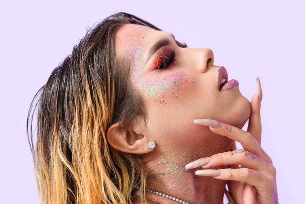 Fashionable young transgender woman with glitters on body against color background - Foto, immagini