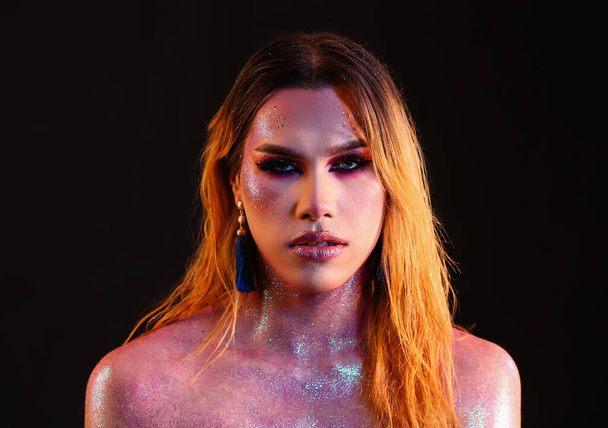 Alla moda giovane donna transgender con brillantini sul corpo contro sfondo scuro - Foto, immagini