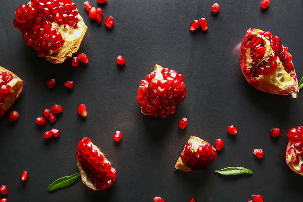 Tasty ripe pomegranate pieces on dark background - Fotó, kép