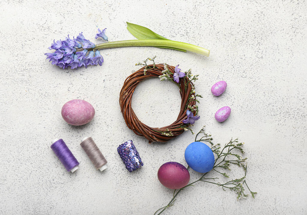 Состав с пасхальным венком, цветами, яйцами и нитями на светлом фоне - Фото, изображение