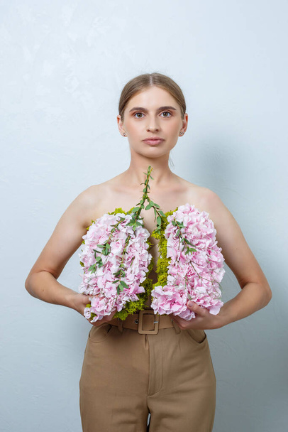 Beautiful confident woman holding fresh spring flowers in her hands. Fresh flowers in the hands of a fair-haired woman - Foto, imagen