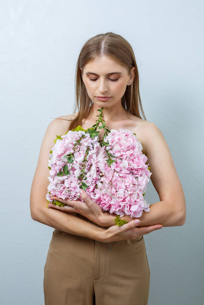 Hermosa mujer segura sosteniendo flores frescas de primavera en sus manos. Flores frescas en las manos de una mujer de pelo rubio - Foto, imagen