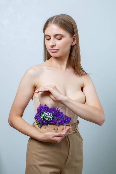Gyönyörű, magabiztos nő friss tavaszi virágokat tart a kezében. Friss virágok egy szép hajú nő kezében. - Fotó, kép