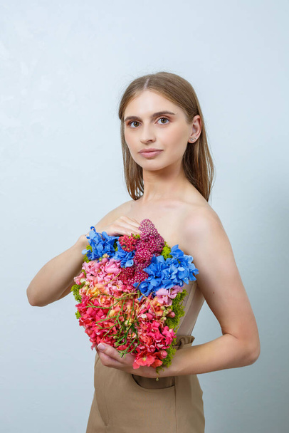 Красивая уверенная в себе женщина, держащая в руках свежие весенние цветы. Свежие цветы в руках светловолосой женщины - Фото, изображение