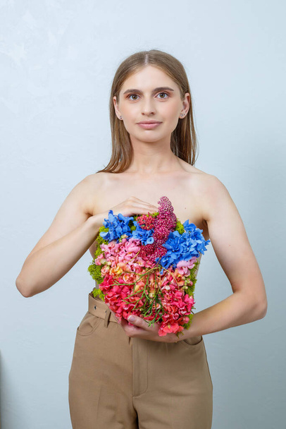 Schöne selbstbewusste Frau mit frischen Frühlingsblumen in den Händen. Frische Blumen in den Händen einer blonden Frau - Foto, Bild