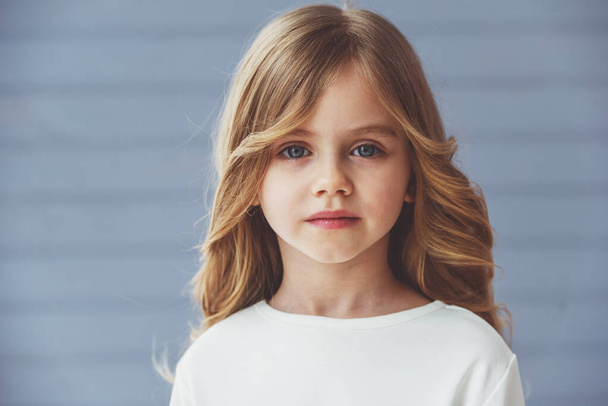 Portret van mooie kleine blonde meisje met mooie grote ogen kijken camera - Foto, afbeelding