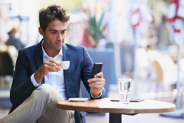 Przerwa ekspresowa. Zdjęcie młodego biznesmena czytającego tekst w kawiarni na świeżym powietrzu.. - Zdjęcie, obraz