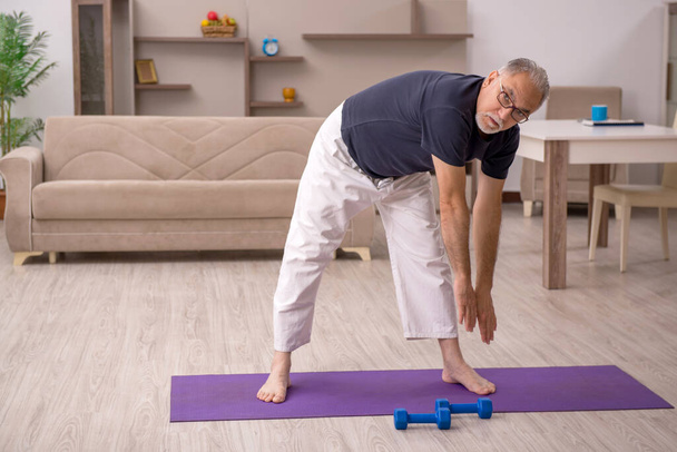 Старий робить спортивні вправи вдома
 - Фото, зображення