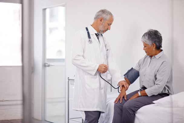 A routine checkup. A doctor measuring a mature patients blood pressure. - Photo, Image