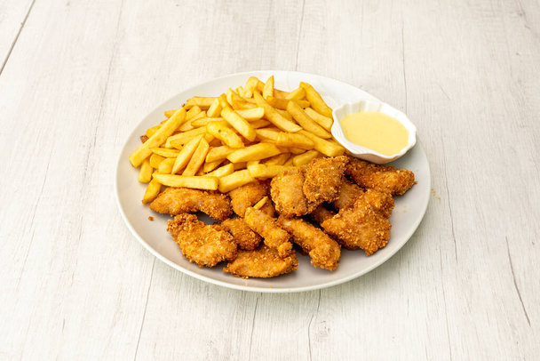 Placa de menú con tiras de pollo rebozadas, papas fritas y salsa para mojar - Foto, imagen