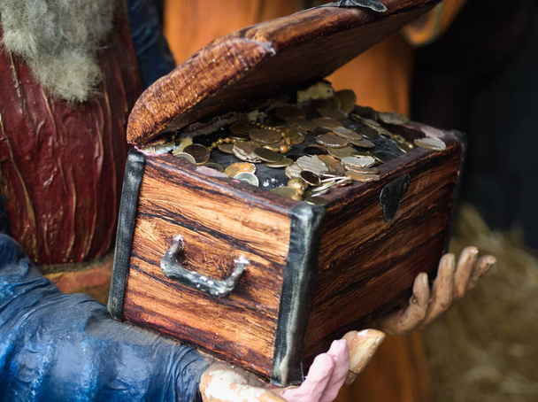 Χέρια κρατώντας ξύλινο στήθος θησαυρού με κέρματα - Φωτογραφία, εικόνα