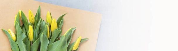 Horizontal web banner with yellow tulips on gray concrete with copy space. Background for womens day, 8 March Valentines day, 14 february. Flat lay style, top view, mockup, template, overhead - Fotoğraf, Görsel