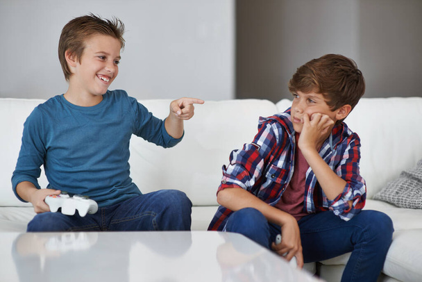 Haha, tu as encore perdu. Tourné d'un jeune garçon riant de son ami après l'avoir battu à un jeu vidéo. - Photo, image