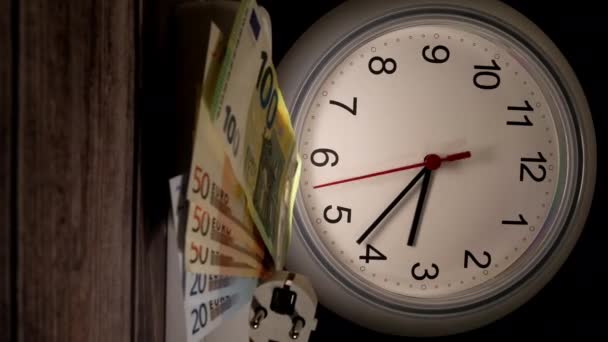 Közelkép a pénzről és egy konnektor egy órával mögöttük. időintervallum - Felvétel, videó
