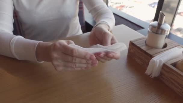 Mujer en una mesa en un restaurante se frota las manos con una servilleta antibacteriana - Imágenes, Vídeo