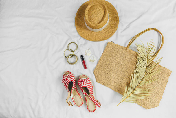 Yazlık plaj aksesuarları hasır şapka, çanta, beyaz arka planda sandaletler. Yaz konsepti, tatil kıyafetleri, yaz tatilleri. - Fotoğraf, Görsel