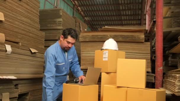 Asijský muž pracovník v bezpečnostní uniformě a hard hat pomocí skeneru čárových kódů pro kontrolu objednávek zásilek ve skladu zásilek, továrna na výrobu papíru pro obalový průmysl, logistické přepravní služby. - Záběry, video