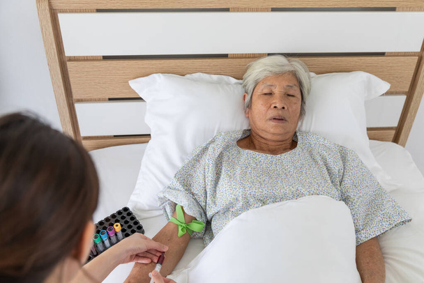 медсестра использовать шприц крови пожилой пациентки в больничной палате - Фото, изображение