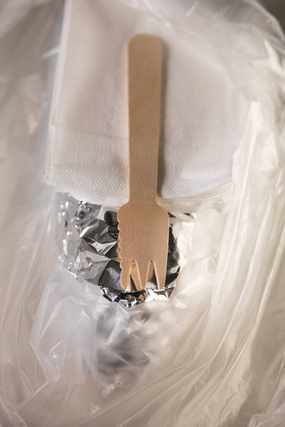 Un paquete de comida rápida para llevar en aluminio y plástico con un tenedor de madera y servilletas. - Foto, imagen