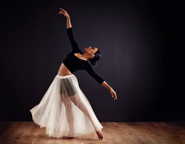 Elegance personified. Young female contemporary dancer using a soft white white skirt for dramatic effect. - Foto, imagen