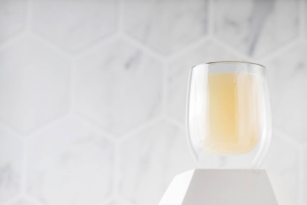 Healthy bone broth in a transparent mug on a pedestal on a light background. Copy space. - Photo, Image