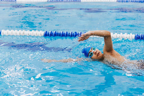 latijn jongeman tiener zwemmer atleet dragen pet en bril in een zwemtraining in het zwembad in Mexico Latijns-Amerika - Foto, afbeelding