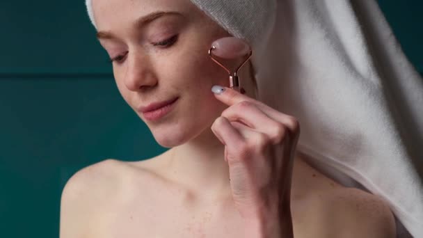 Freckled woman glowing skin using natural jade roller for facelifting rejuvenation face massage. Close-up portrait. Spa body care. Home concept. Rejuvenation - Footage, Video