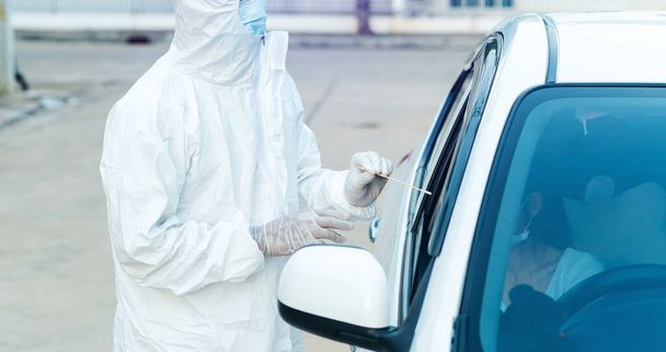 Medical worker in protective suit screening woman Driver to Sampling secretion to check for Covid-19. check,taking nasal swab specimen sample from patient through car  - Foto, imagen