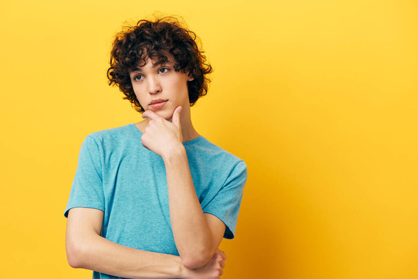 tiener guy blauw t-shirts op een gele achtergrond portret - Foto, afbeelding