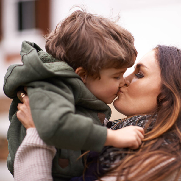 Gib deiner Mutter einen Kuss. Aufnahme einer schönen Mutter, die ihren kleinen Sohn hebt und ihm einen Kuss gibt. - Foto, Bild