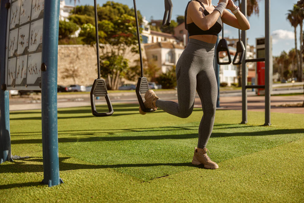 Athletic woman training on exercise equipment at park - Foto, afbeelding