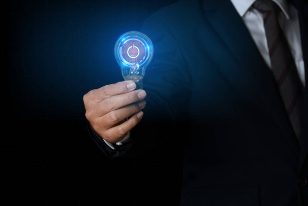 Businessman holding glowing light bulb with power button symbol. innovation concept. - Photo, Image