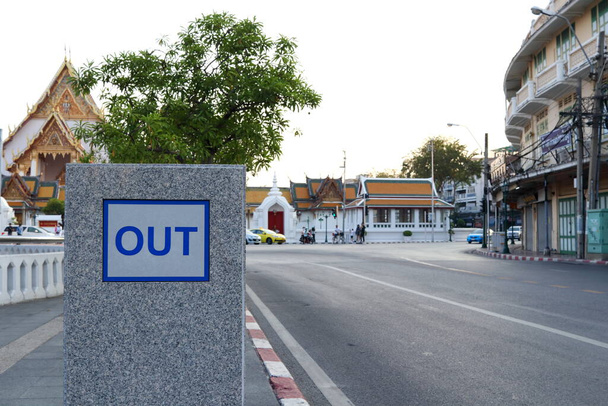 Uit woord op wit frame, blauwe brief op grijze muur besid roade in Bangkok en wazig tempel achtergrond, Thailand. Meld je weg van gebouw. - Foto, afbeelding