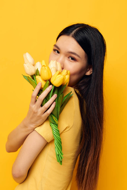 woman with Asian appearance with a bouquet of yellow flowers romance studio model unaltered - Foto, immagini