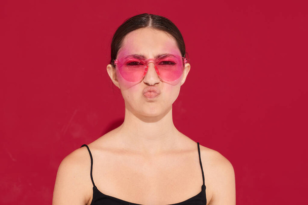 pretty woman pink glasses bright makeup posing black jersey pink background unaltered - Photo, Image