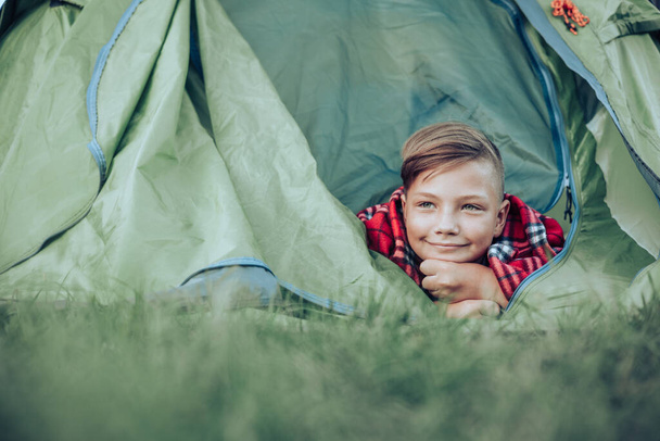 10代の少年はテントの中で遊んで横たわっていた。週末の屋外. - 写真・画像