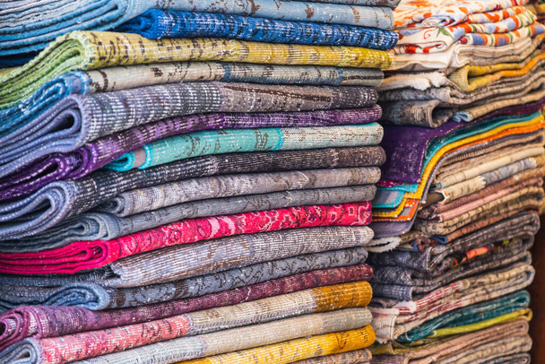 Grandes filas de piezas de tela hechas de algodón, poliéster y otros materiales en diferentes colores y estampados de ropa, enfoque suave - Foto, Imagen