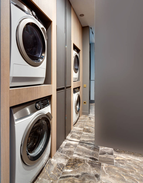 Máquina de lavar roupa moderna em lavandaria com piso de mármore preto amarelo branco interior tons naturais de madeira sustentabilidade ecológica. Sala de serviços públicos. Estilo de vida sustentável - Foto, Imagem