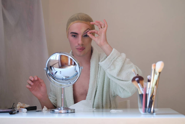 Drag queen person removing false eyelashes and wearing bathrobe. - 写真・画像