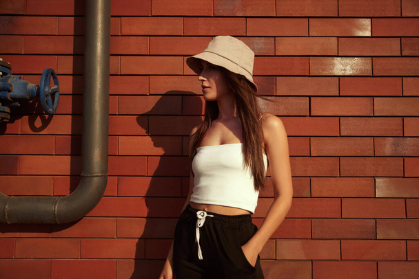 Stylish woman standing near brick wall - Zdjęcie, obraz