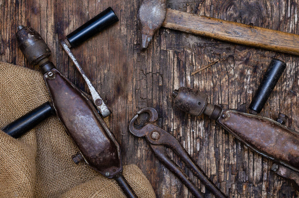 Hand Tools. Pliers, drill, hammer and Rough Fabric Bagging on Dark Wooden Background. Cracked wooden surface with cracks and splinters. Selective focus. - Valokuva, kuva